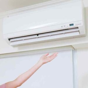 white ac unit with woman's hand feeling the breeze in a Summerwood residence